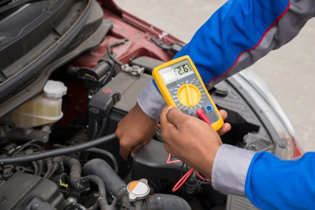 Auto mechanic testing an electrical circuit using a multimeter