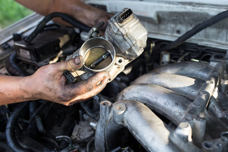 Auto mechanic doing a tune up on a throttle body