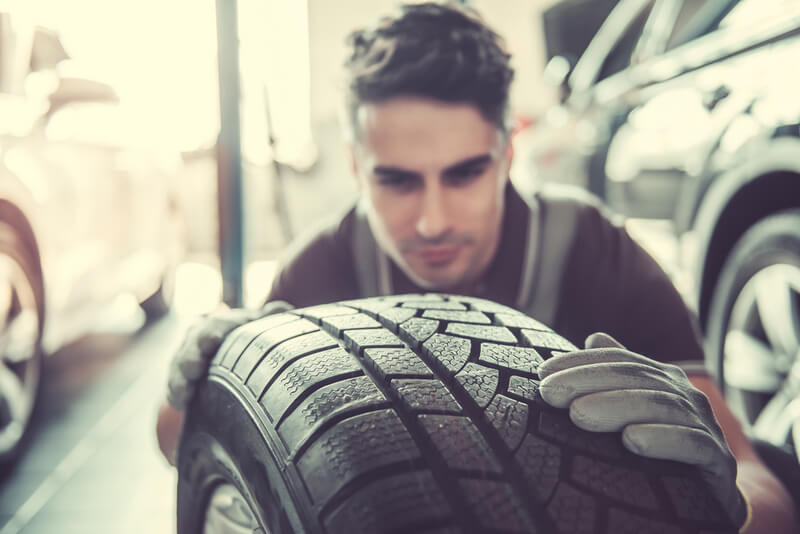 Auto mechanic inspecting a tire for flat