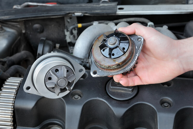 Auto mechanic replacing a bad water pump