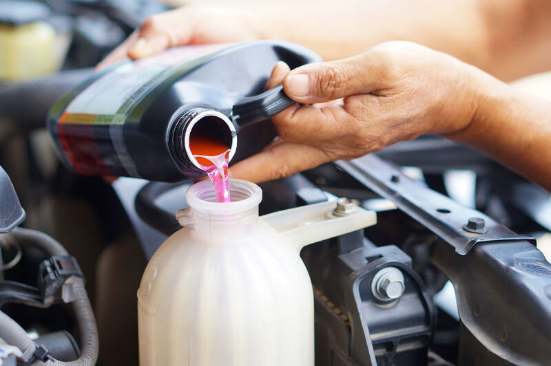 Auto mechanic refilling a coolant system