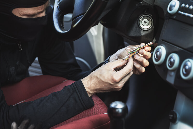 Car thief hot-wiring a car ignition switch