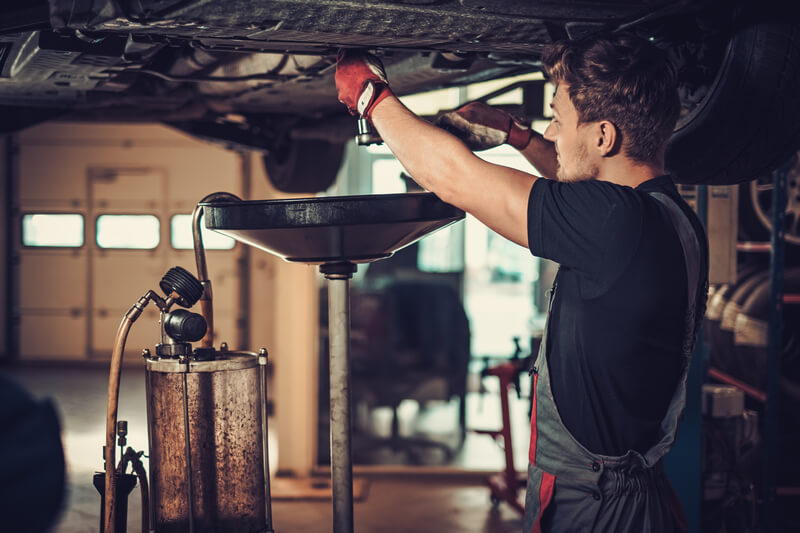 Auto mechanic performing oil change