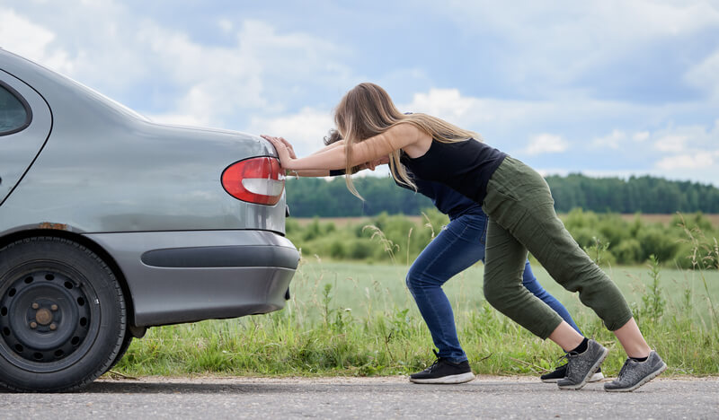 Man and woman push-starting a car