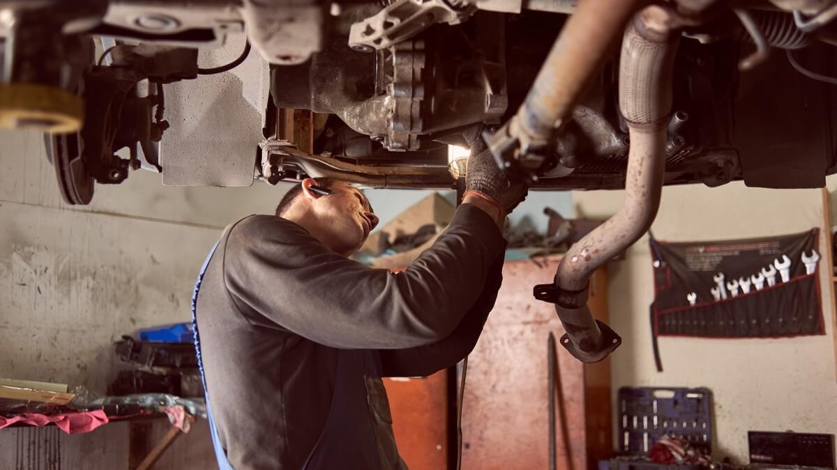 auto mechanic replacing exhaust pipe