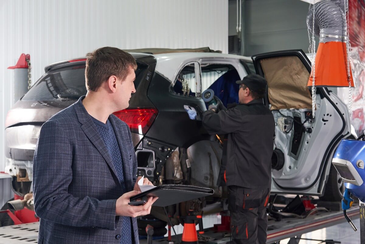 Repair shop owner overlooking mechanic