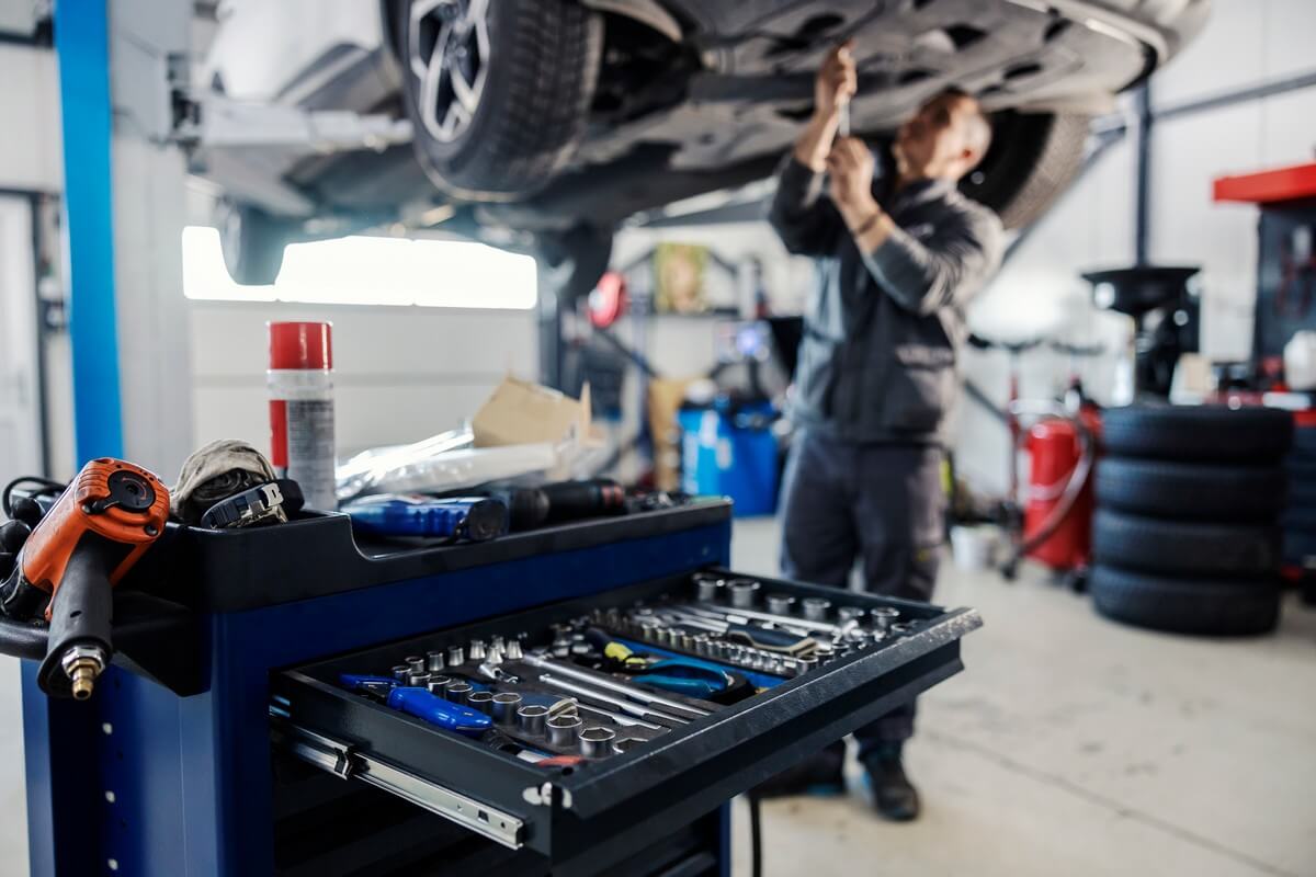 auto mechanic working on a car with tool chest