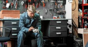 Auto mechanic using phone during downtime